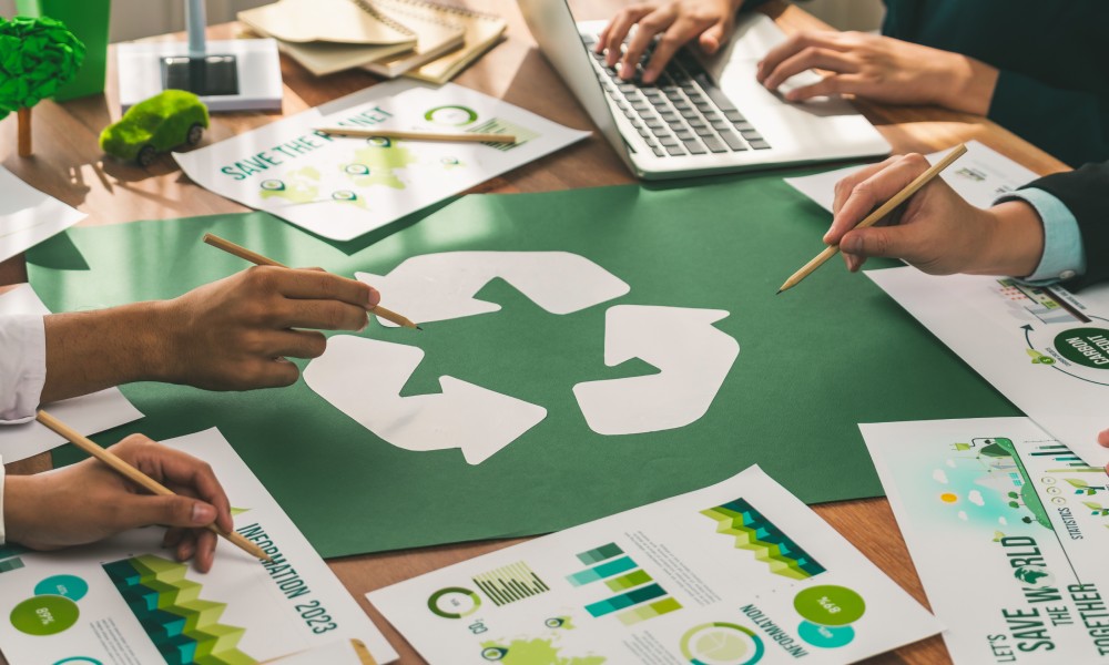 Business people sitting at a table with statistics documents on the table and a big recycling symbol in the middle of the table.