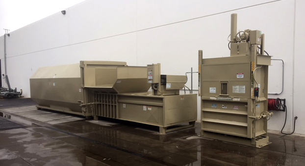 Two brown self-contained waste machines. The long brown is a compactor and the vertical machine is a baler.
